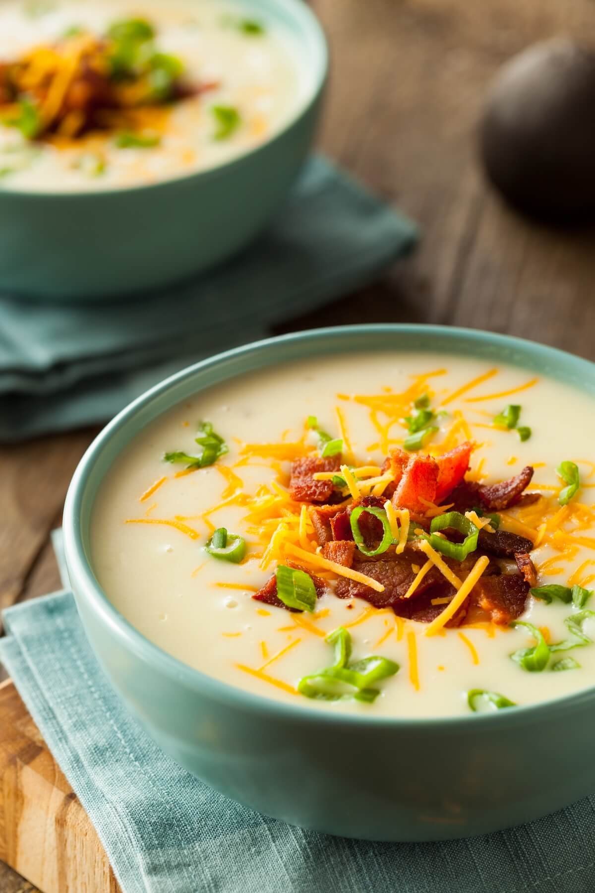 Bowl of creamy baked potato soup topped with cheese and bacon bits — a cozy fall family dinner recipe