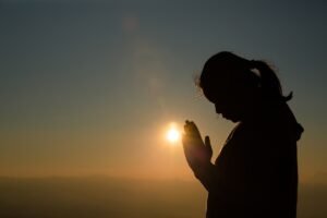 Woman praying at sunrise.