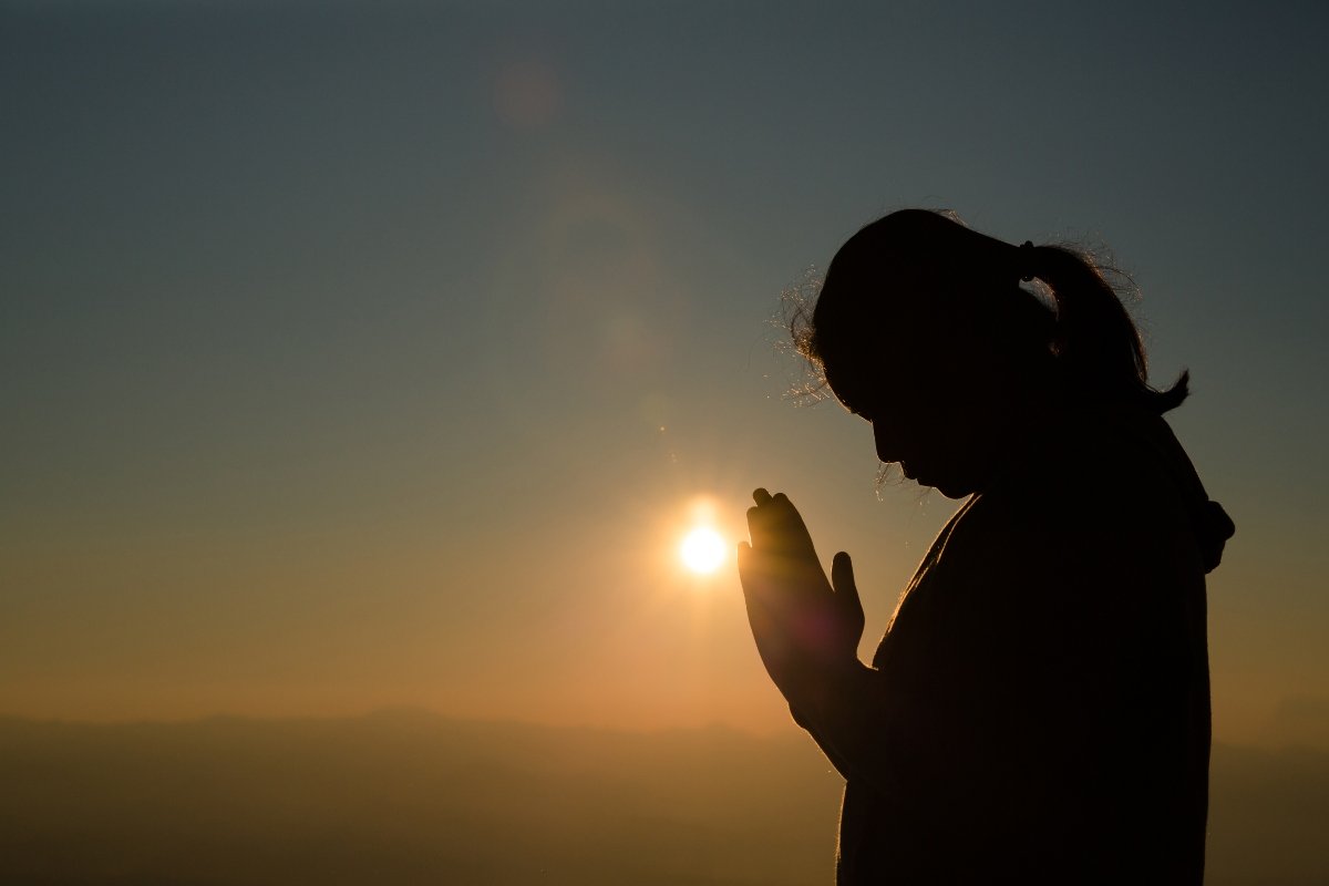 Woman praying at sunrise.
