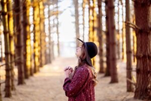 Woman praying peacefully in the forest.