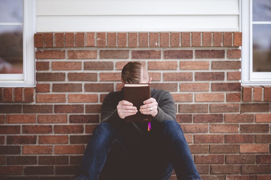 Man holding a bible while sitting alone and praying.